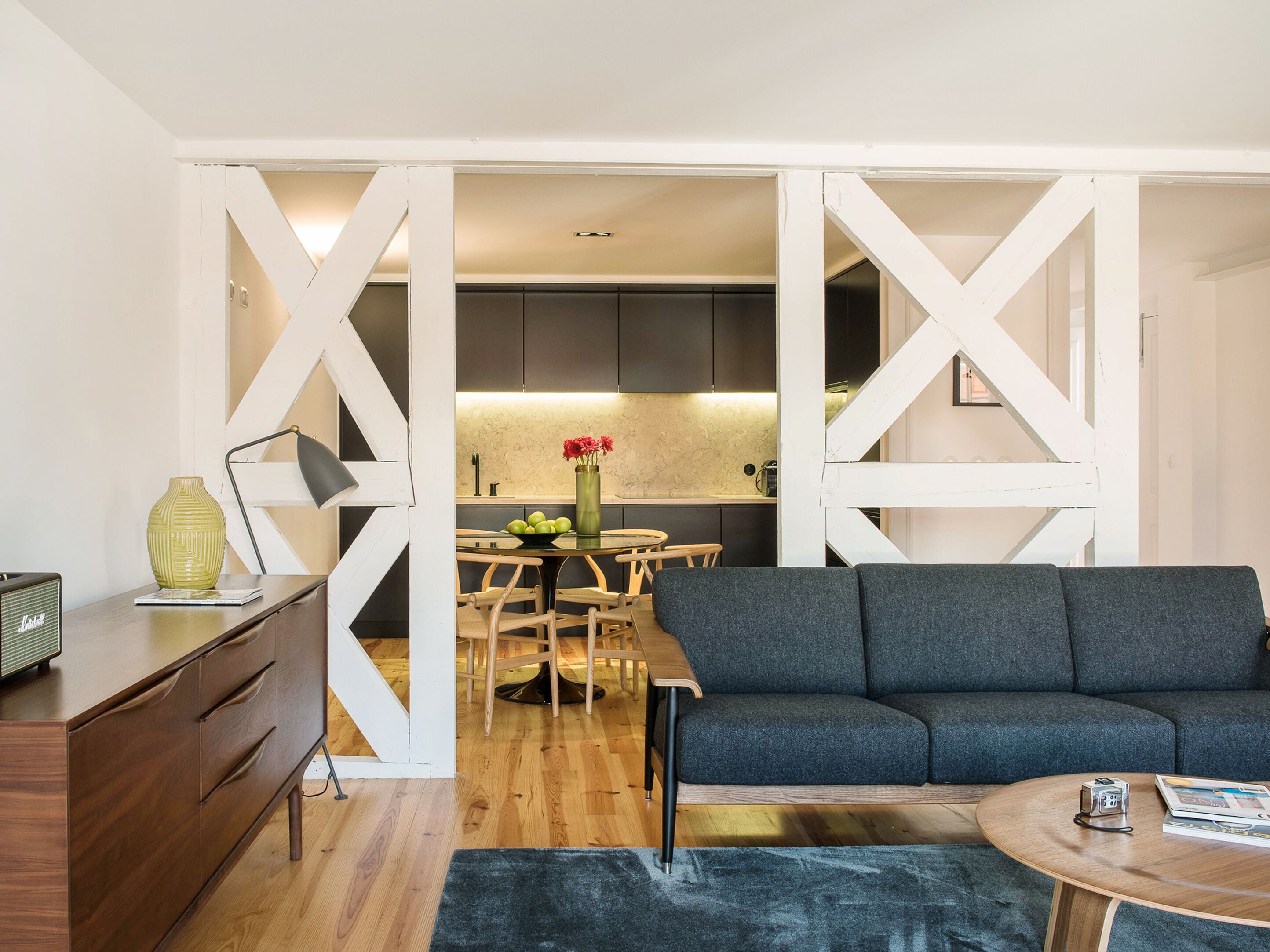 A modern living room with a grey sofa, wooden coffee table, and a dining area with a wooden table and chairs.