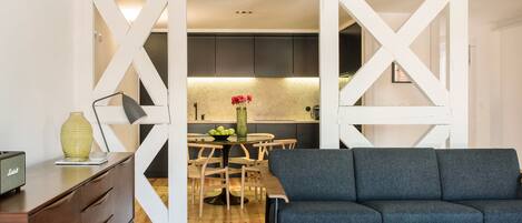 A modern living room with a grey sofa, wooden coffee table, and a dining area with a wooden table and chairs.