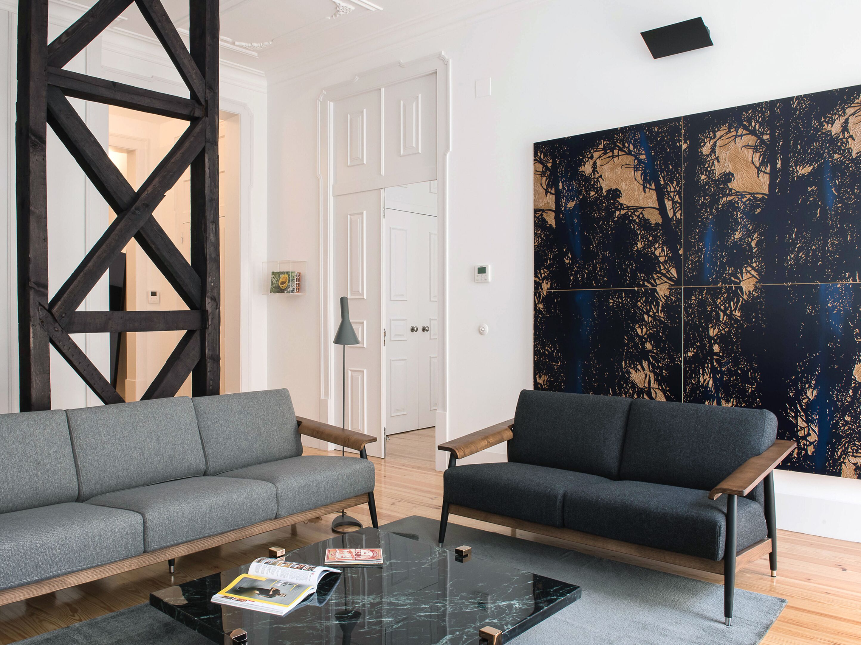 A modern living room with a grey sofa, a wooden coffee table, and a large abstract painting on the wall.