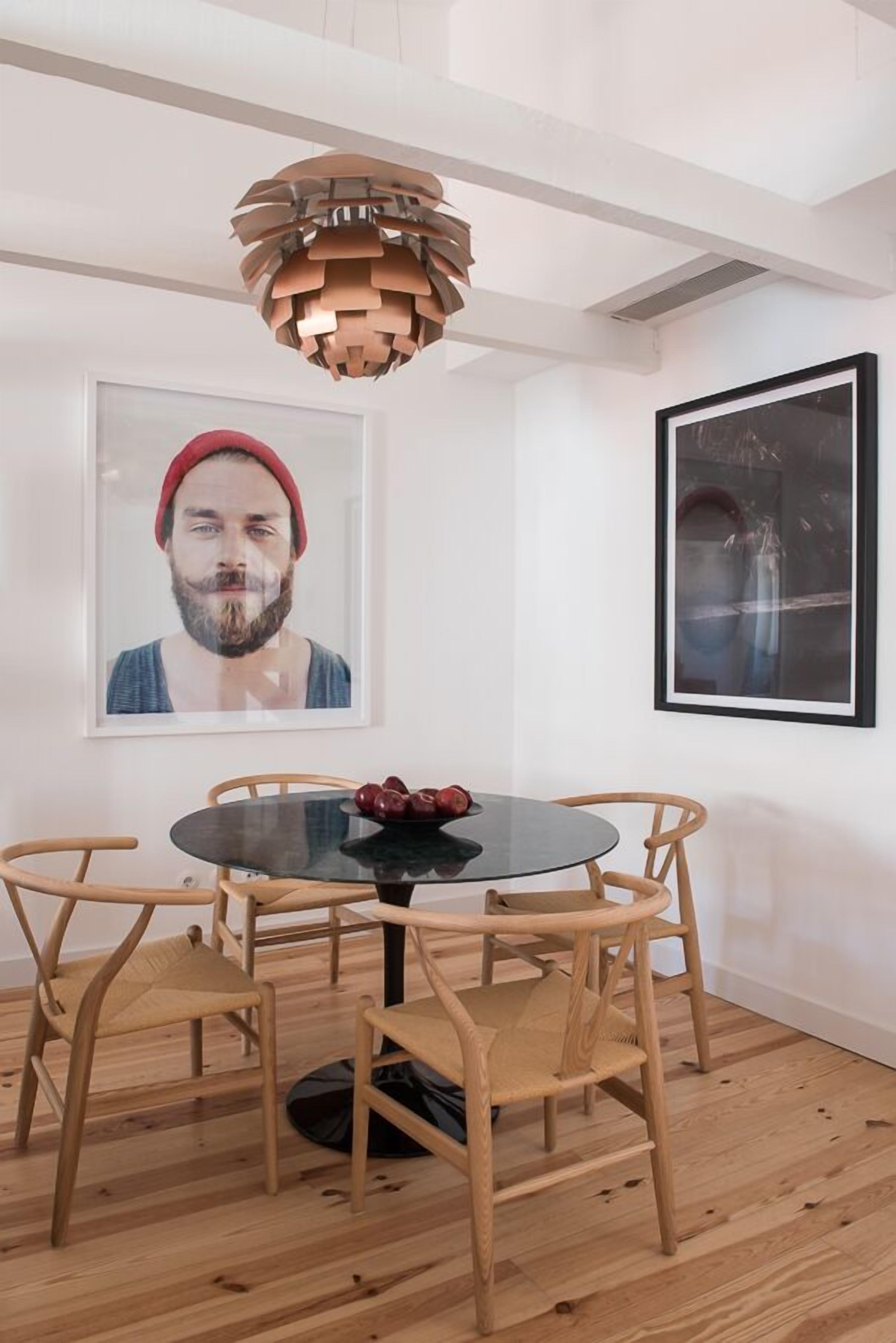 A dining area with a round table, wooden chairs, and a unique pendant light.