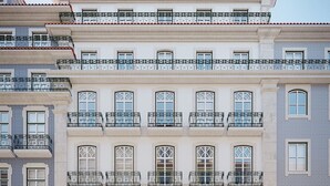 Un immeuble à plusieurs étages doté de balcons, de grandes fenêtres et d’une porte verte.
