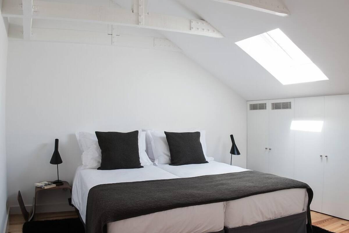 Un dormitorio con cama, paredes blancas, tragaluz y armario.