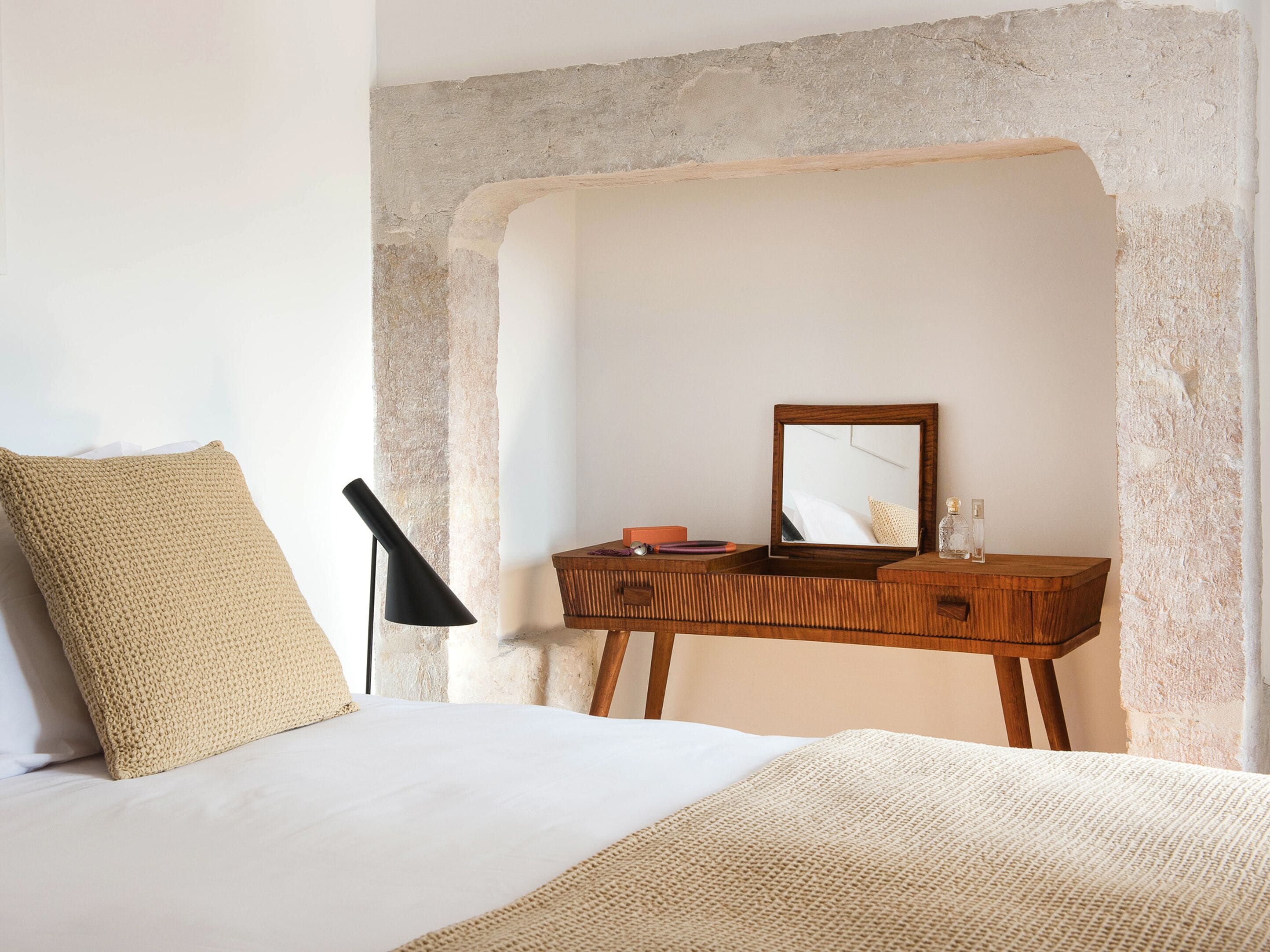 Un dormitorio con una cama, un aparador de madera, un espejo y una lámpara.