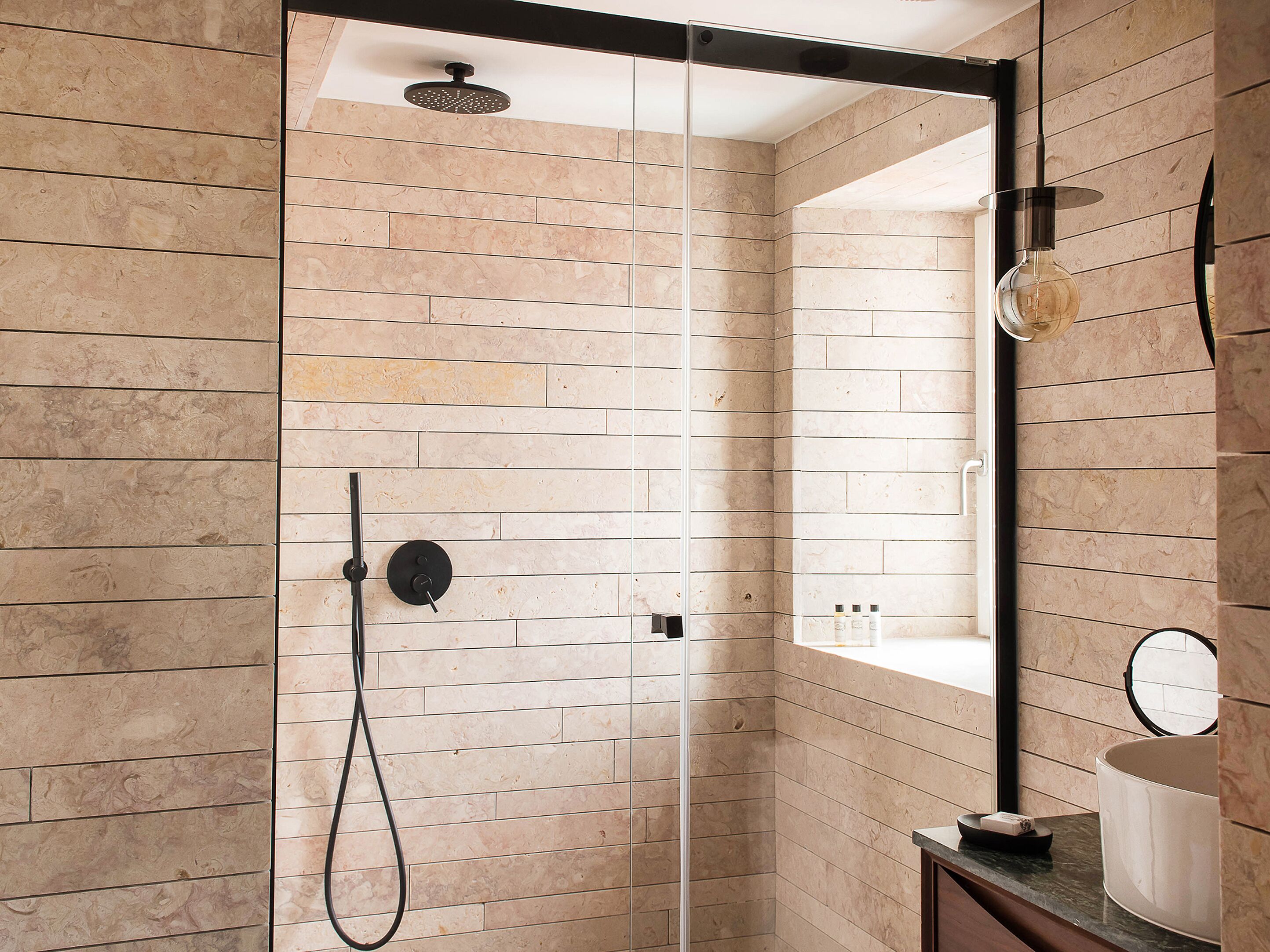 Un baño moderno con cabina de ducha de vidrio, un espejo redondo y una zona de lavabo minimalista.