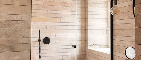 Un baño moderno con cabina de ducha de vidrio, un espejo redondo y una zona de lavabo minimalista.