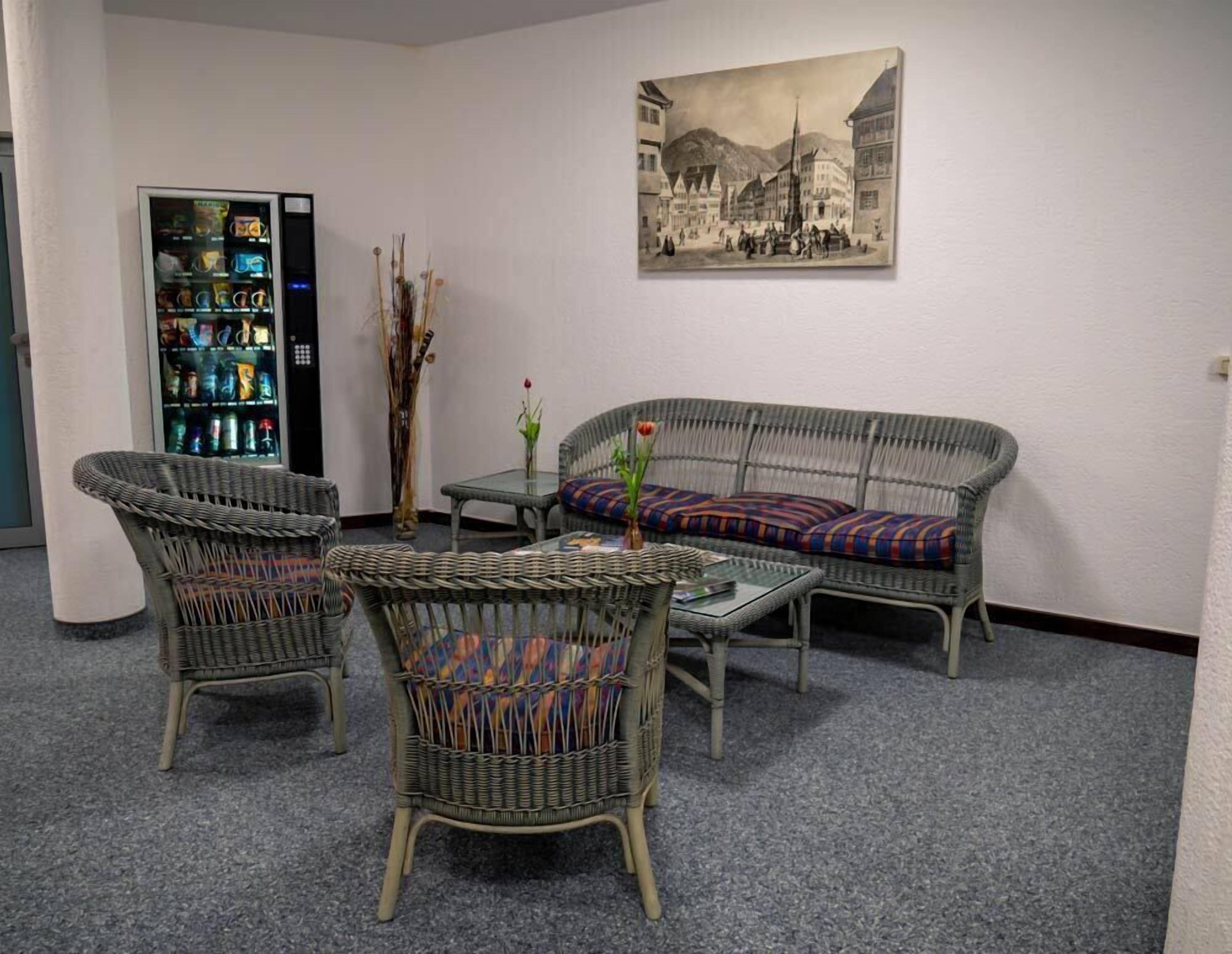 A room with wicker furniture, a vintage painting, and a beverage dispenser.