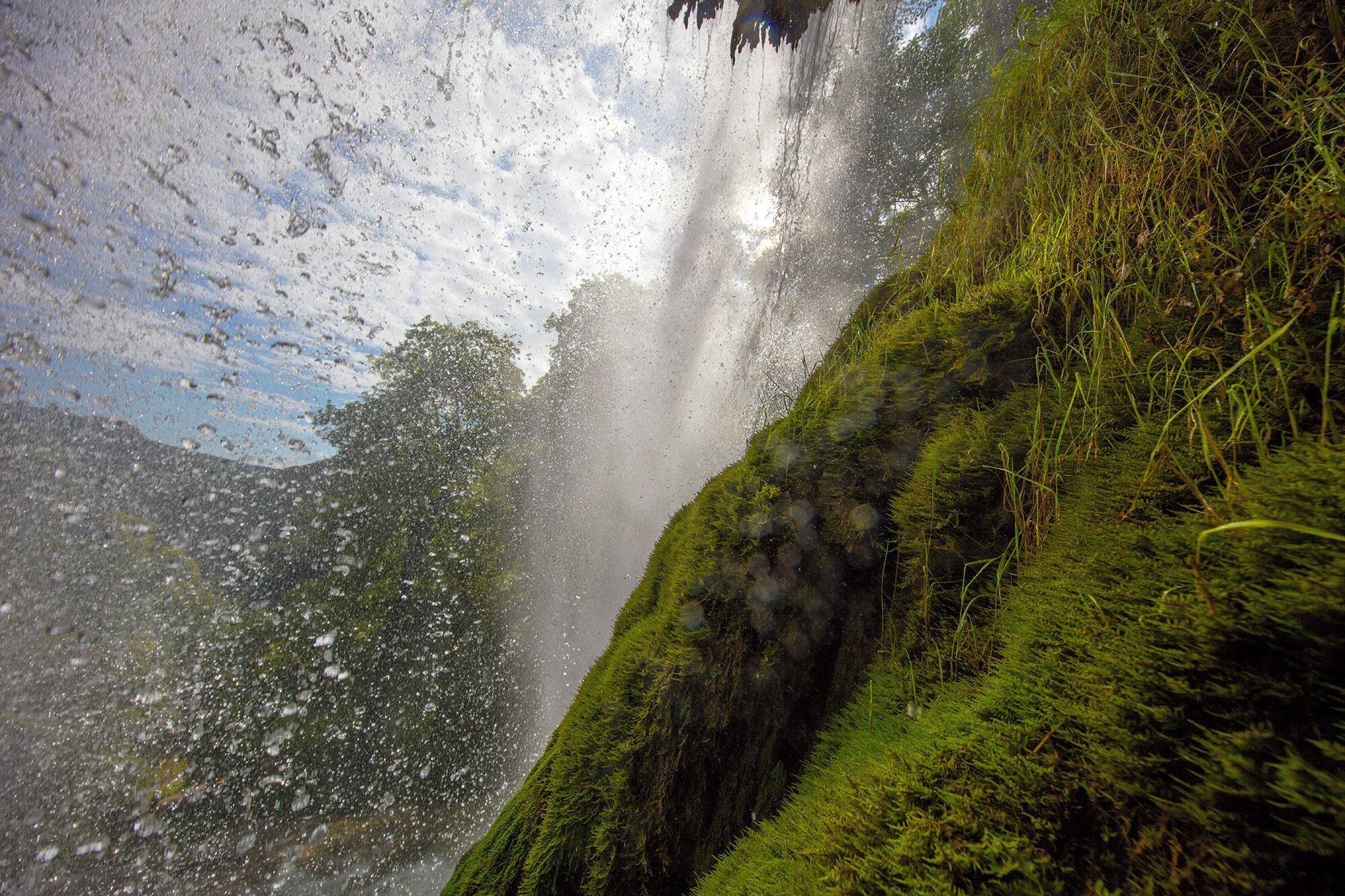 Une cascade d’eau se déversant sur une falaise couverte de mousse.