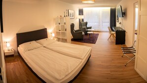 Una habitación de hotel moderna con una cama grande, un escritorio, una silla y un televisor.