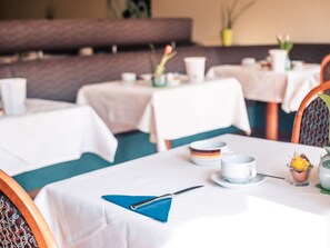 A dining area with tables set for meals, including plates, cups, and cutlery. - Hotel Quellenhof Bad Urach (Bad Urach)