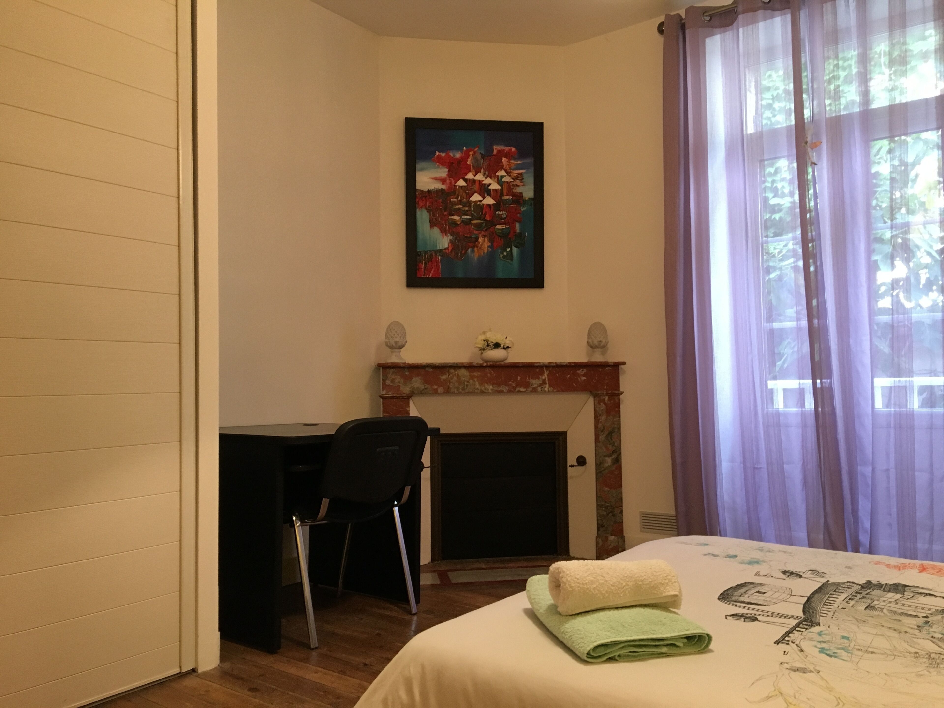 Ein Hotelzimmer mit Bett, Schreibtisch, Sessel, Kamin und einem Bild an der Wand.