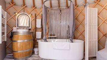 Un baño rústico con un barril de madera, una bañera independiente y una ducha con revestimiento de madera.