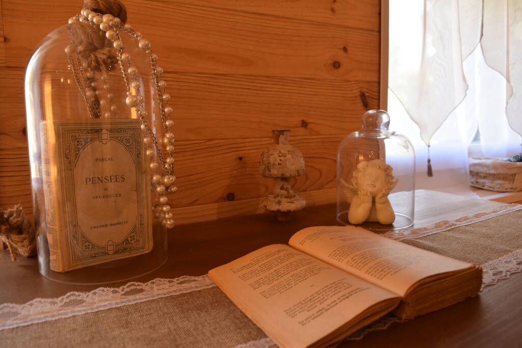Una mesa de madera con un libro, una botella y un frasco de vidrio.