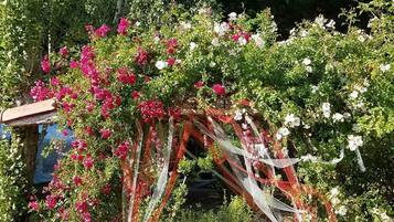 Ein Garten mit einem Zierbogen, geschmückt mit rosa und weißen Blumen und roten und weißen Bändern.