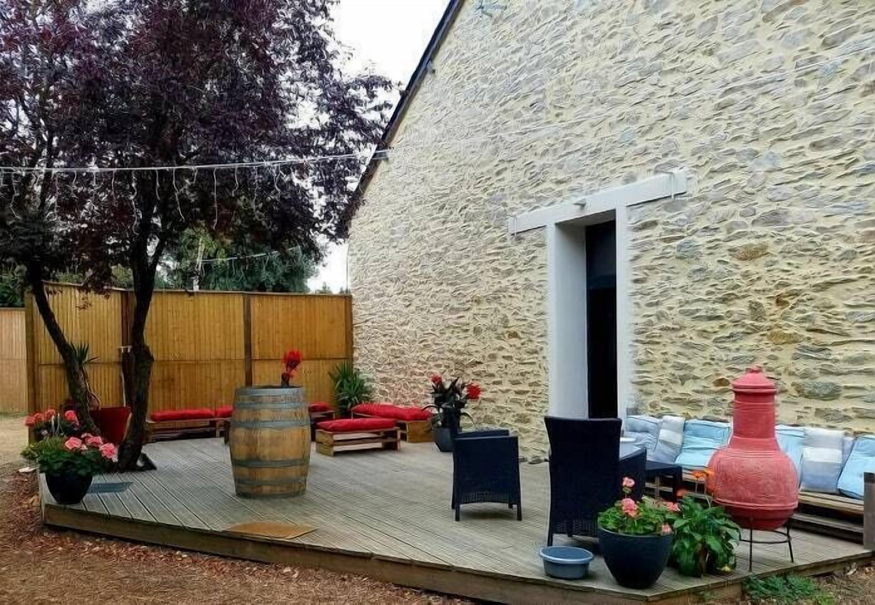 An outdoor patio with seating, a stone wall, and a wooden deck.