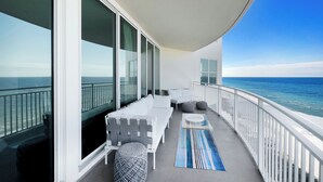 Ein Balkon mit weißem Sofa, Hocker und Tisch mit Blick auf den Ozean.