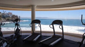 A gym with treadmills and stationary bikes, overlooking a coastal view. - Gorgeous Ocean Front Condo -Rosarito Beach -VIEWS! (Rosarito)