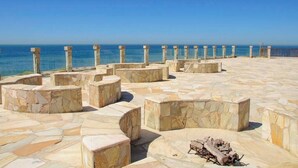 A stone-paved outdoor area with seating and a fire pit, overlooking the sea. - Gorgeous Ocean Front Condo -Rosarito Beach -VIEWS! (Rosarito)
