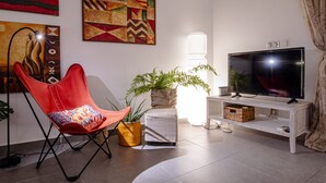 A living room with a red chair, a television, and artwork on the wall. - Grand Case Bleu Marine Sea Side (Grand-Case)