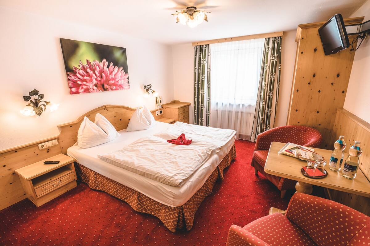 A hotel room with a bed, a desk, a chair, a television, and a window with curtains.