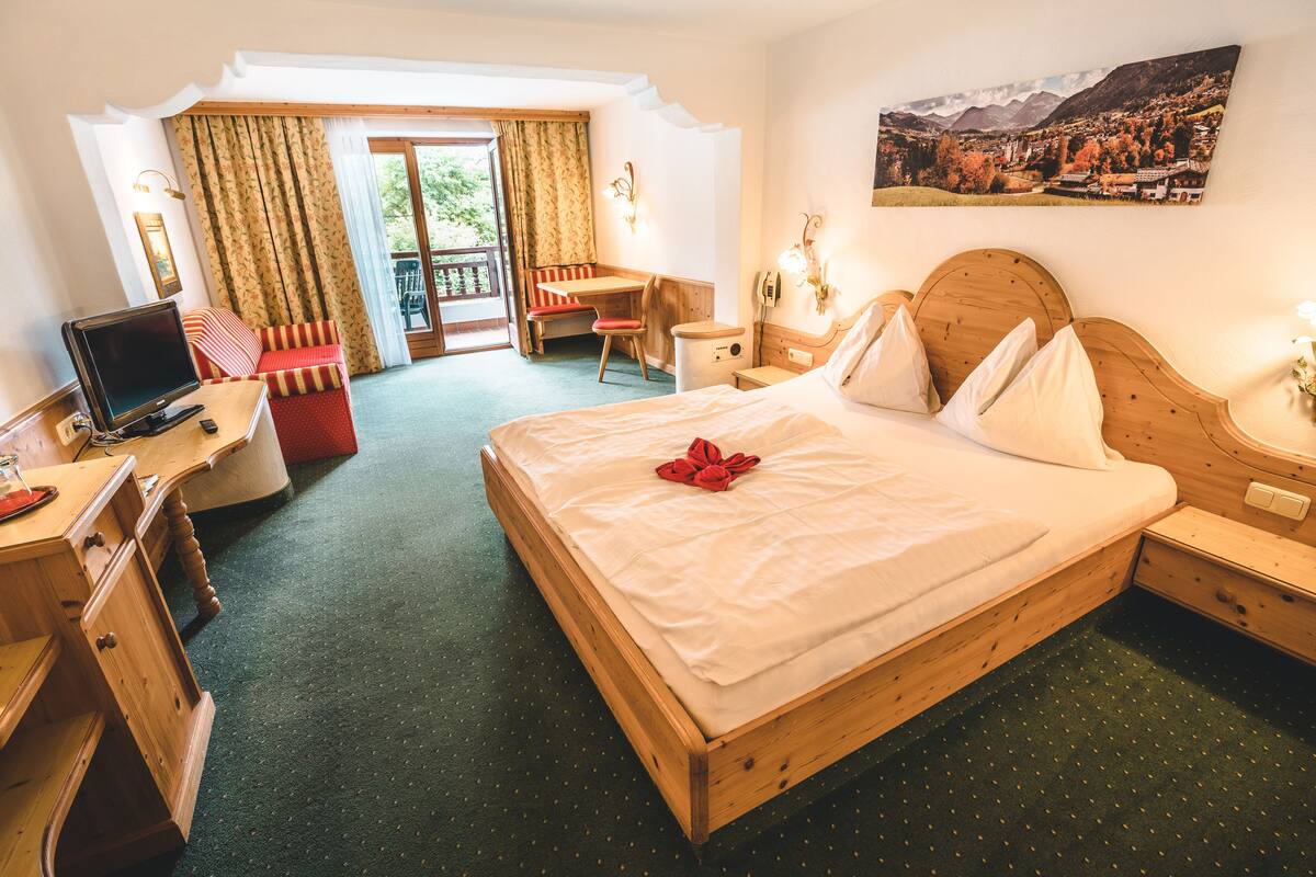 A hotel room with a wooden bed, a desk, a chair, and a computer.