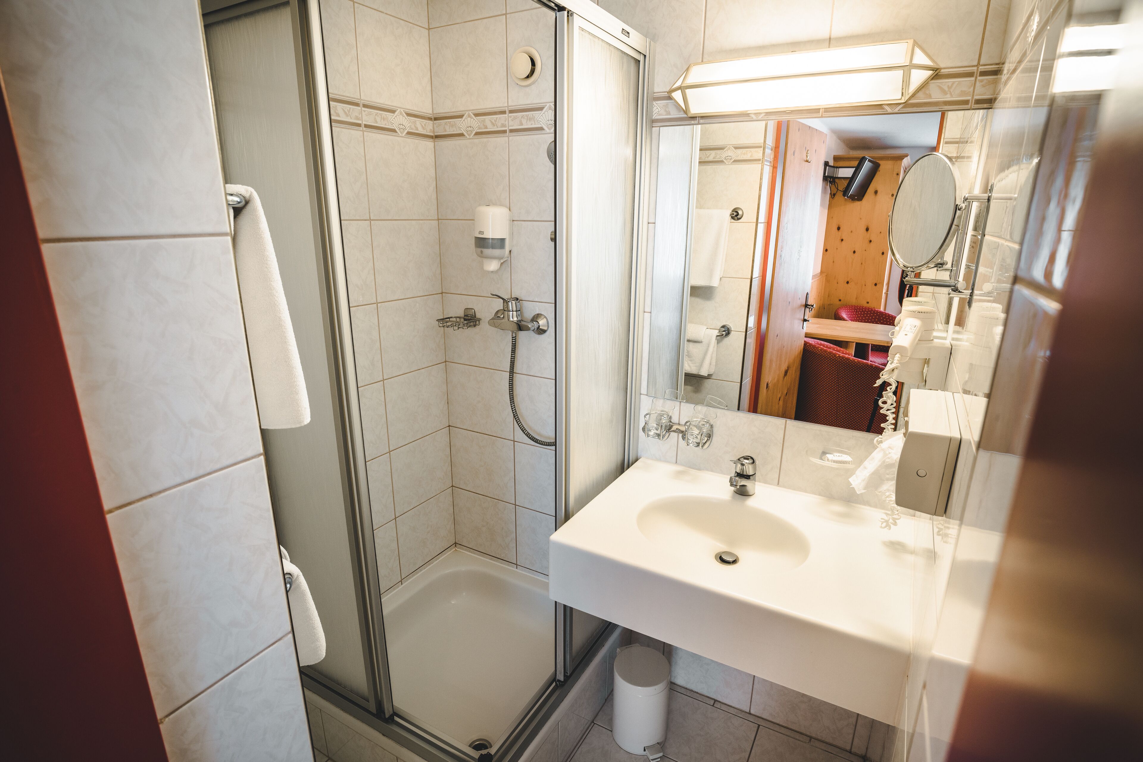 A bathroom with a shower, a sink, and a mirror.