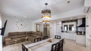 Un espace de vie moderne comprenant un coin repas, une cuisine et un grand lustre.