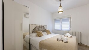 Une chambre à coucher avec un lit, un miroir, une fenêtre avec des stores et un radiateur.