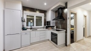 Une cuisine moderne avec des meubles blancs, un four à micro-ondes encastré, une cuisinière et un lave-vaisselle.