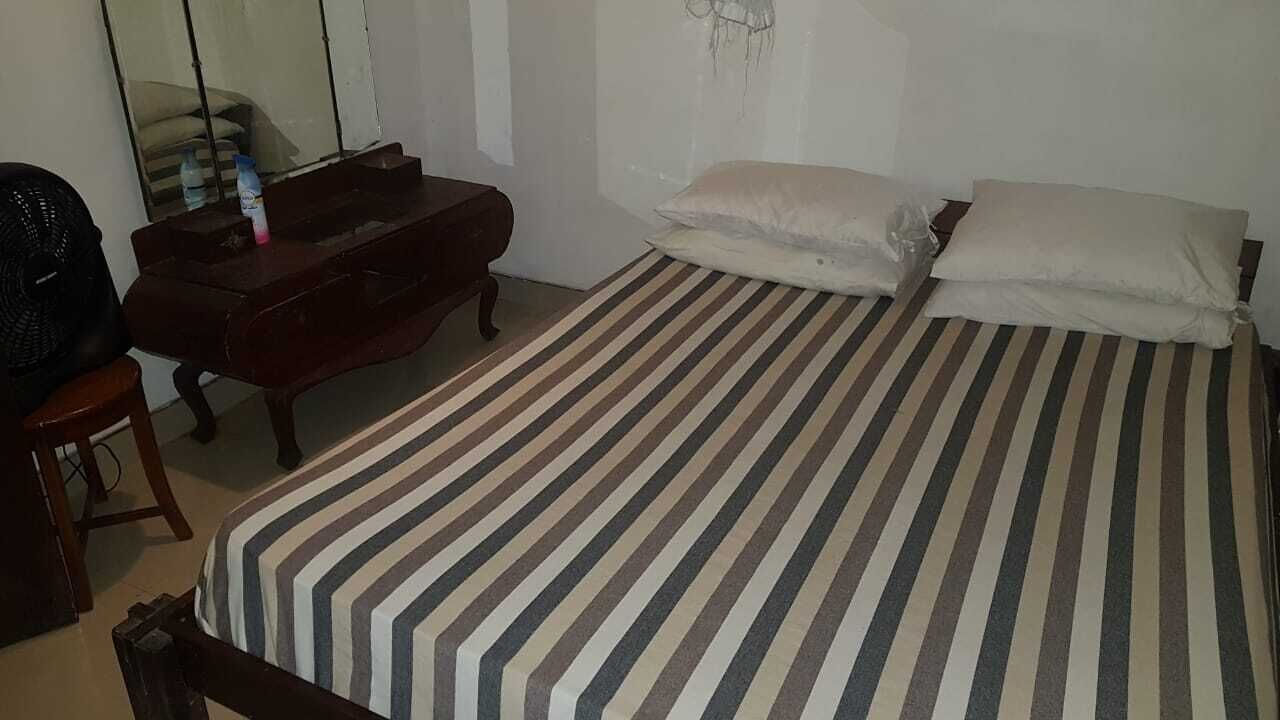 Ein Schlafzimmer mit Bett, Kommode, Spiegel und Ventilator.