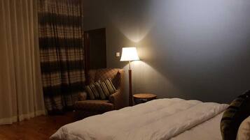 Ein Hotelzimmer mit Bett, Stuhl, Lampe und einem Fenster mit Vorhängen.