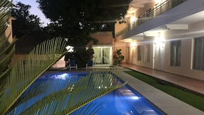 A swimming pool with a clear blue water surface, surrounded by a well-maintained lawn and palm trees.