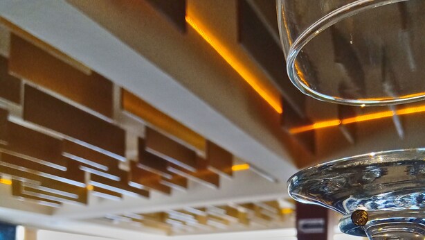 Un interior de restaurante con mesas y sillas, un ventanal grande y una estructura de vidrio decorativa.