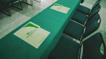 Una mesa de conferencias con mantel verde y una señalización blanca con el logo y el nombre del Hotel Villa Esmeralda.