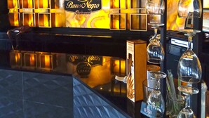Interior de restaurante con una zona de bar, un letrero que dice 'Bano Negro Restaurant', y varias copas de vino expuestas en estantes.