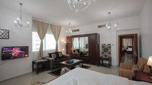 A hotel room with a large bed, a sofa, a coffee table, a TV, and a chandelier. - DM1 Comfortable Apartment in Dubai Marina (Dubai)