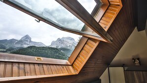 A room with a sloped ceiling and a skylight, offering a view of a mountain range. - ISKÖ Chalets Hotel (Eaux-Bonnes)