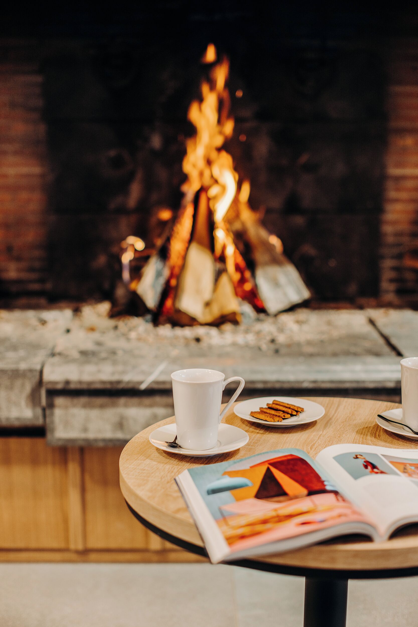 Ein gemütliches Interieur mit Kamin, Tisch mit Buch und zwei Tassen.