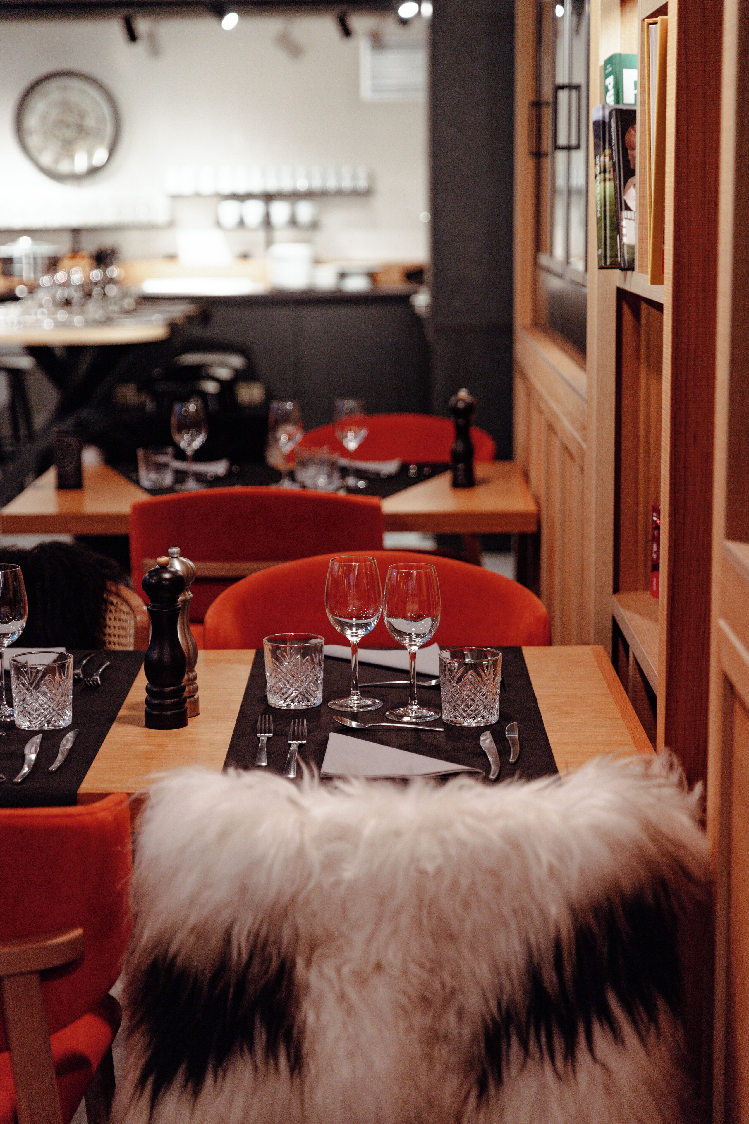 A restaurant interior with tables set for dining, chairs, and a fur-covered object on the floor.