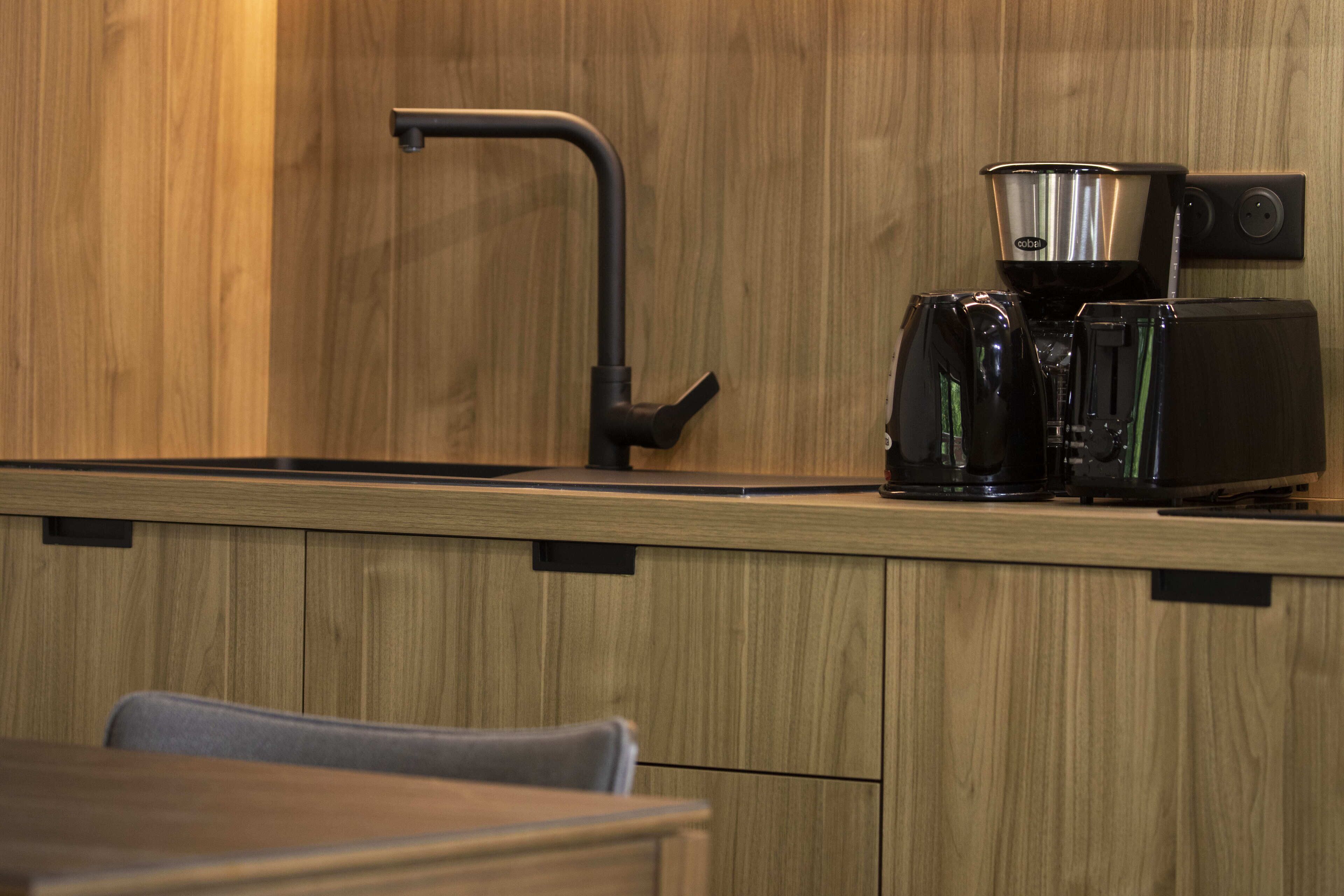 Une cuisine avec des meubles de rangement en bois, une machine à café et un grille-pain.