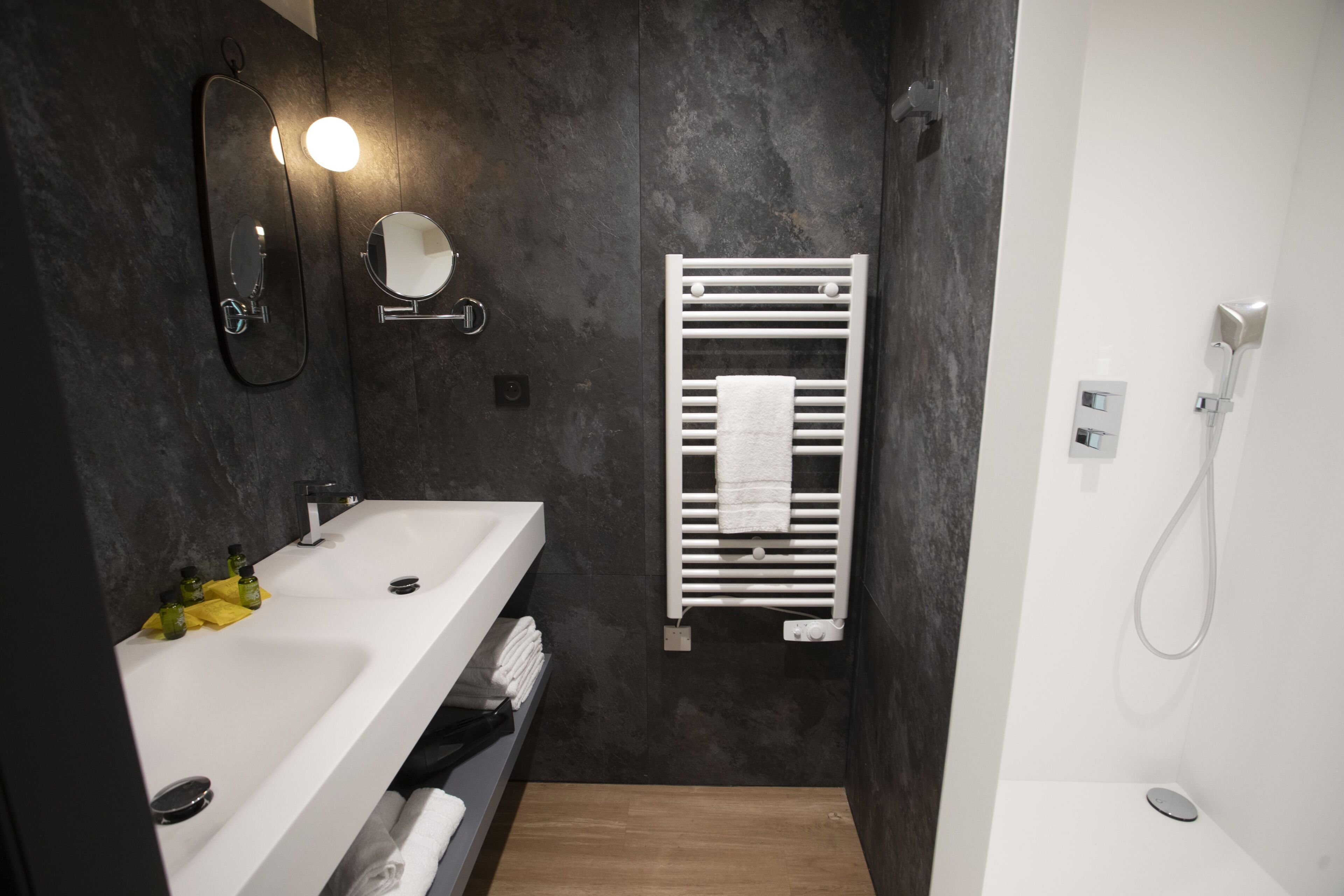 A modern bathroom with a white sink, mirror, and towel rack.