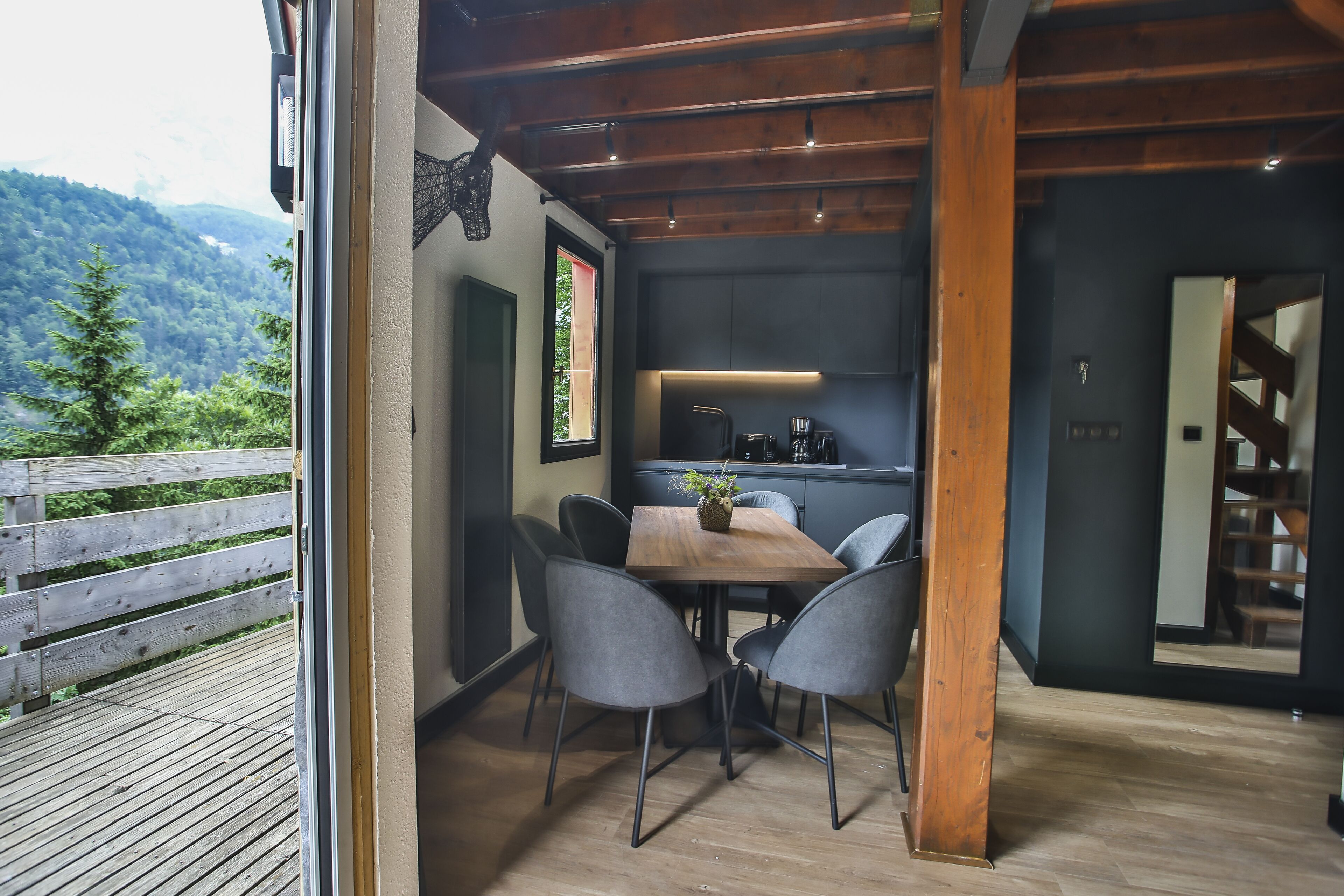 Eine moderne Küche mit dunklen Schränken und einem Holztisch mit Stühlen.