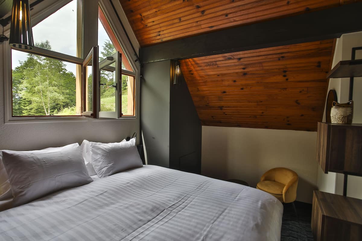 Een slaapkamer met een groot bed, een stoel en een houten plafond.