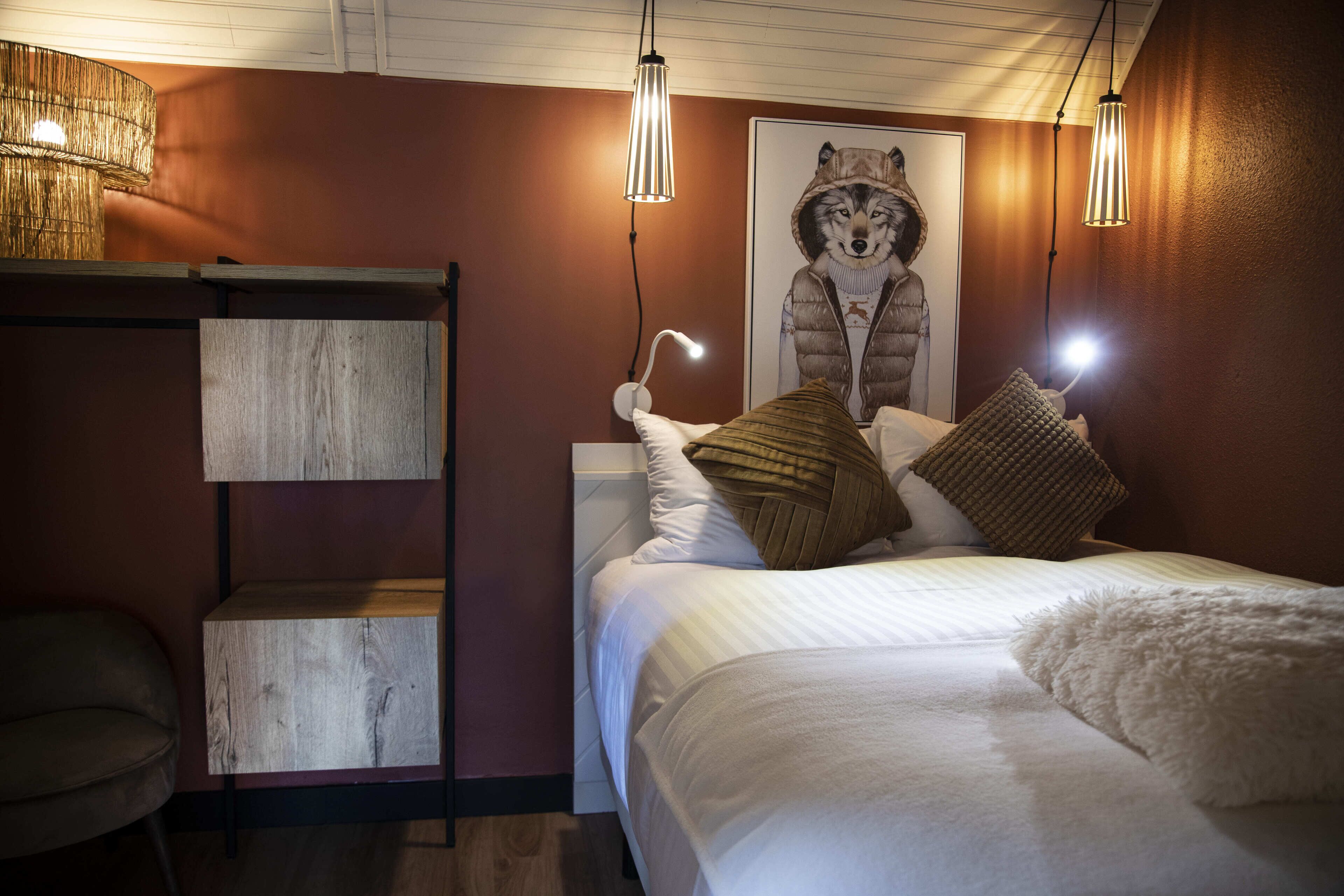 Un dormitorio con una cama nido, un estante de madera, un plaid blanco suave y un cartel con un lobo.