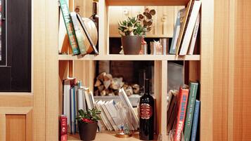 A dining area with a wooden table set for two, a bookshelf with books and decorative items, and a small Christmas tree.