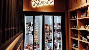 Una tienda con un letrero que dice 'MIAMI!', vitrinas refrigeradas y estantes llenos de diferentes productos.