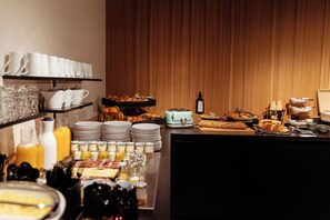 Un bufé con diversos alimentos, entre ellos pan, pasteles y bebidas.