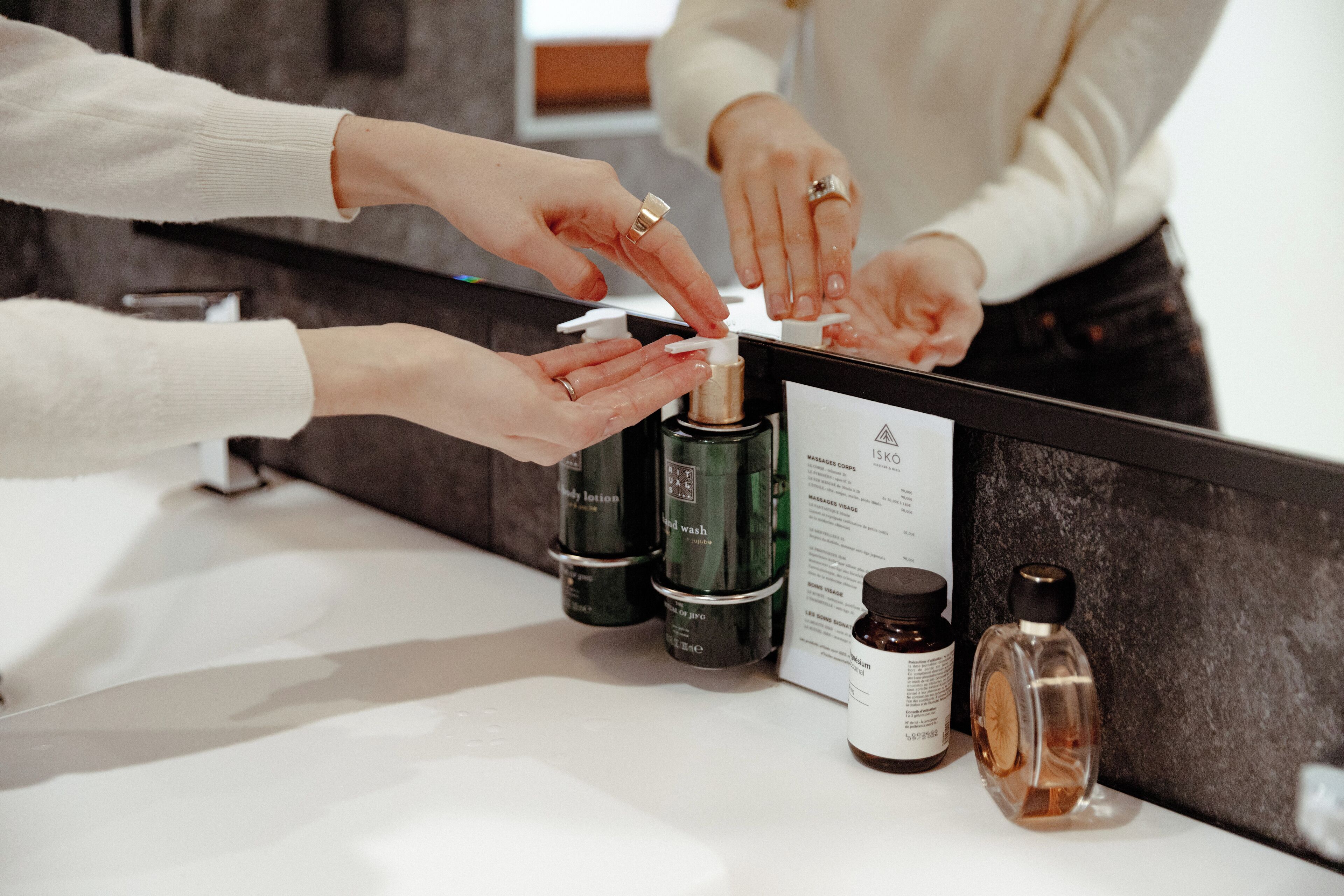 Un meuble-lavabo de salle de bain avec divers produits de toilette, notamment une lotion pour le corps, un savon pour les mains et un flacon de parfum.