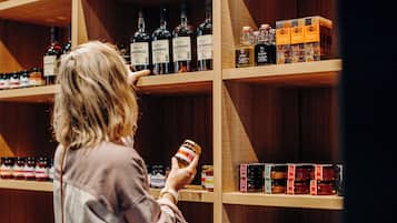 A person examining a jar of jam in a store with shelves of various bottles and jars.