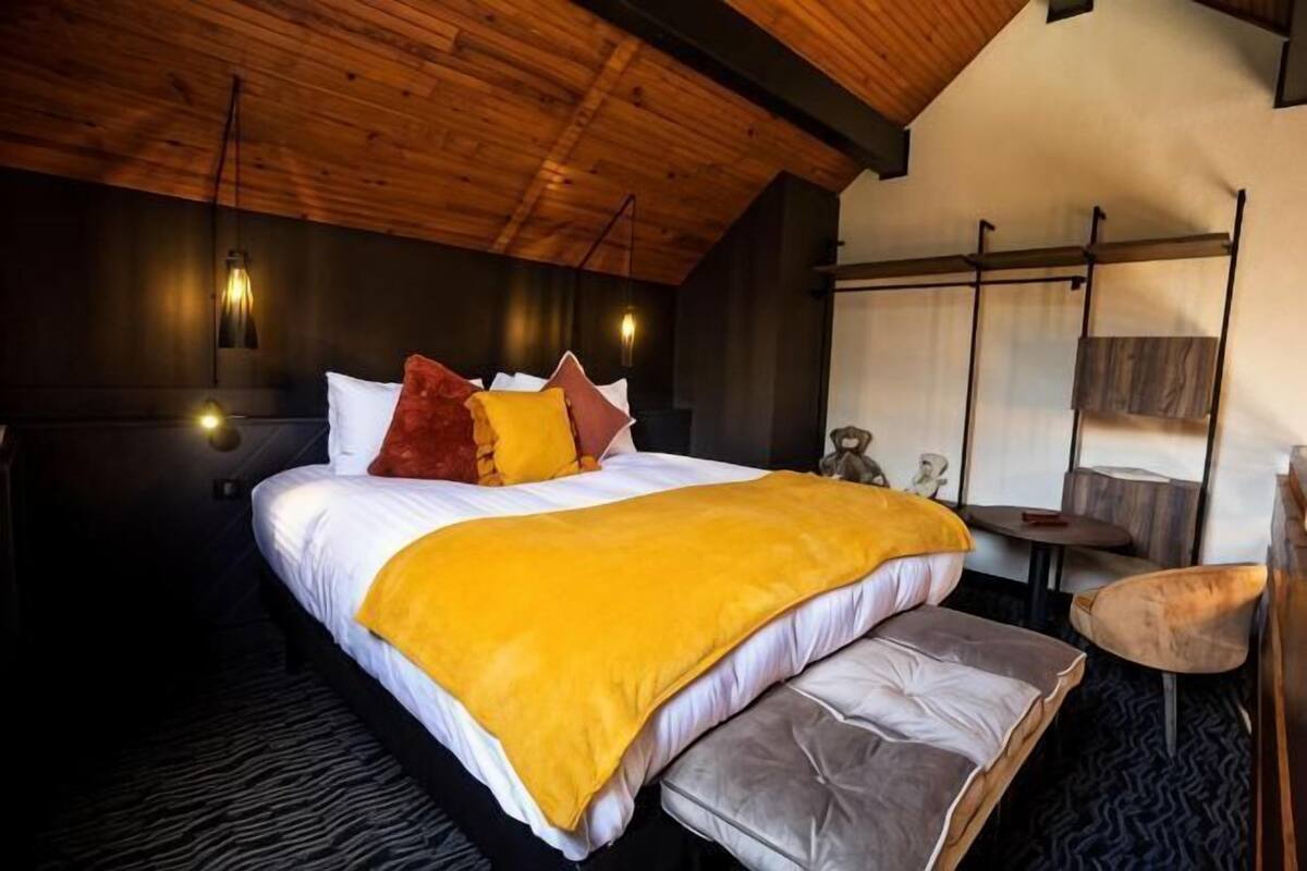 Een slaapkamer met een bed, nachtkastje en stoel.