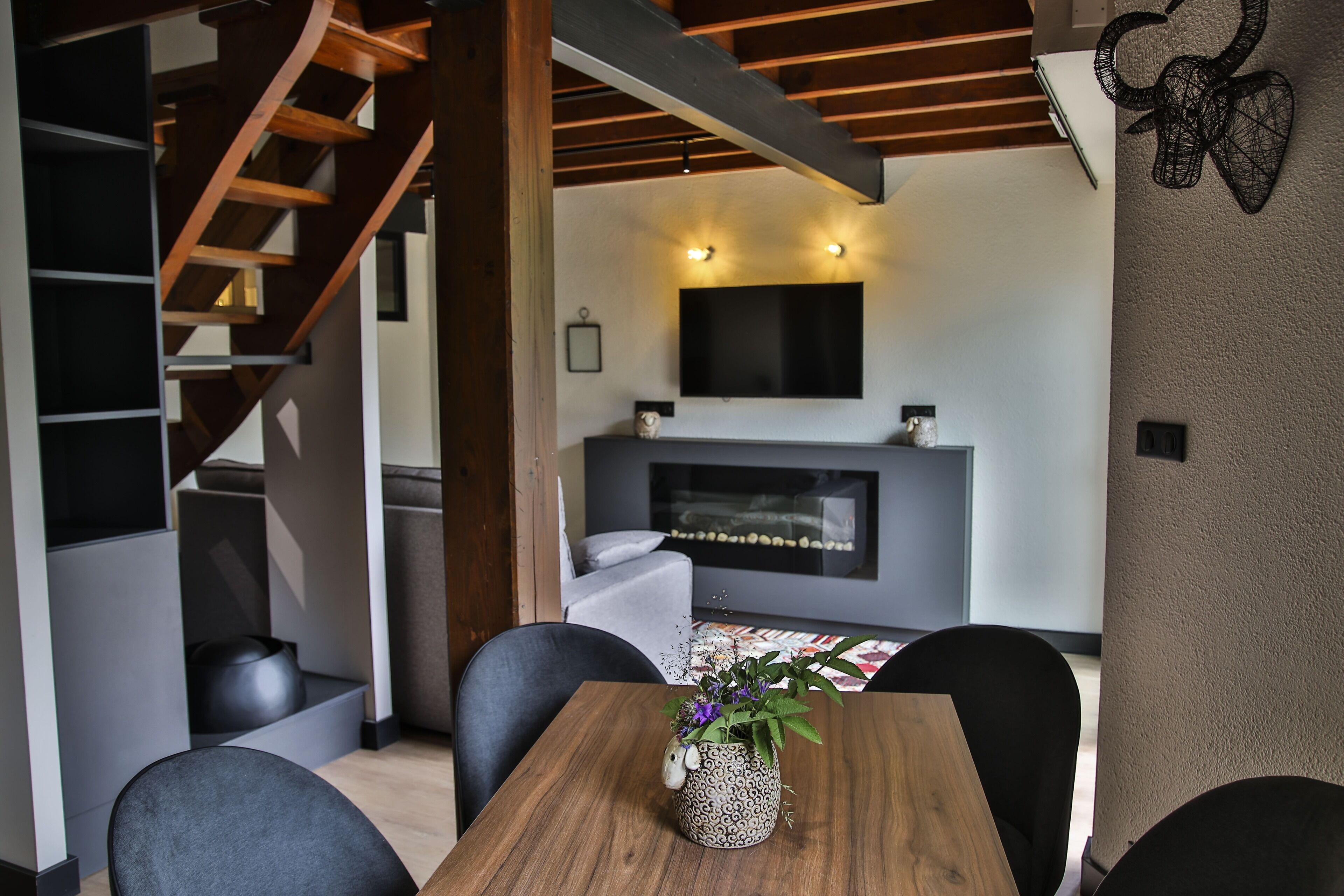 Una sala de estar moderna con chimenea, una escalera de madera y un comedor con mesa y sillas.